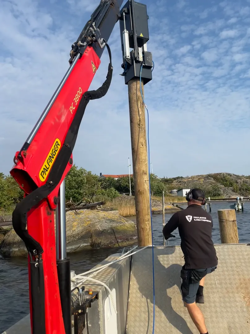 Operatör installerar träpålar från pråm med pneumatisk pålhammare Impact 340